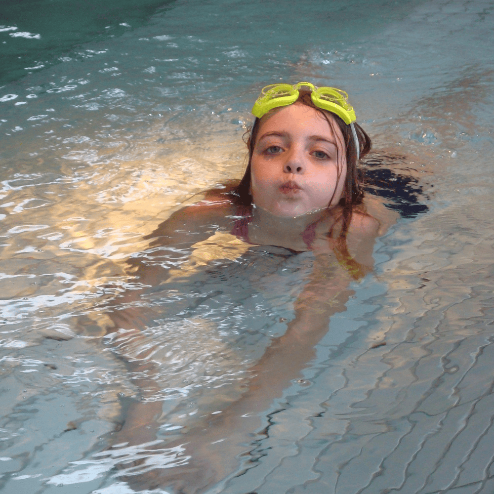 Kind nach dem Seepferdchen beim Schwimmen im Hallenbad
